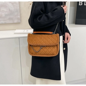 Detail of quilted brown suede bag with faux fur trim and gold chain shoulder strap