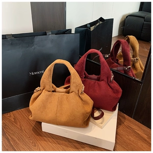 Close-up of suede shoulder bags in ginger and burgundy with pleated texture