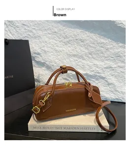 Detail of a brown glossy leather baguette bag featuring golden hardware and logo on art book