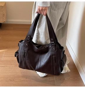 Detailed view of coffee brown tote bag featuring textured leather and stylish zippers