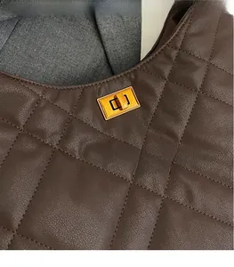 Close-up of a brown quilted leather handbag featuring a gold-tone rectangular metal lock