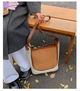 Detail of winter faux shearling tote bag with brown suede flap on a wooden bench