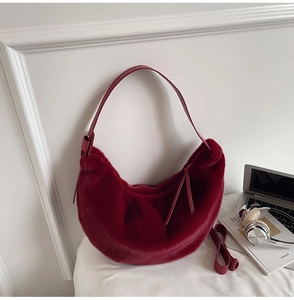 Gros plan du sac hobo en fausse fourrure bordeaux avec bandoulière cuir et pompon chic