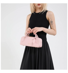 Detail of pink leather baguette bag with gold logo, metal zipper and leather charm accessory