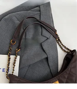 Close-up of brown quilted leather shoulder bag with metallic chain and leather strap
