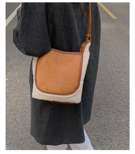 Detail of a brown suede and lamb wool bucket bag with leather edges on a model shoulder