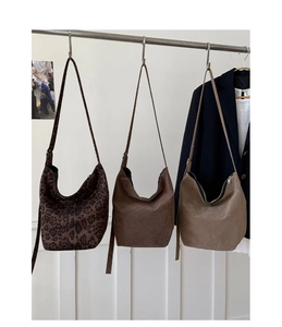 Hobo bags in leopard print and suede brown hanging on a metal rack for display