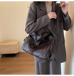 Detail of dark brown leather tote bag with metal zipper and adjustable shoulder strap