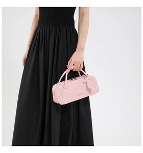 Detail of light pink glossy leather baguette bag with top handles and zipper closure