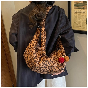 Macro detail of large leopard print suede hobo bag with red pompom charm and retro texture