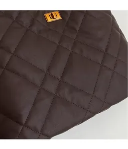 Macro shot of dark brown quilted leather texture and golden metal twist lock detail