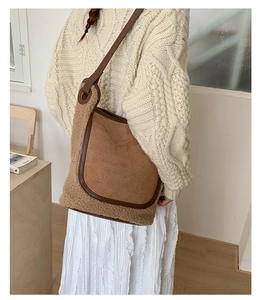 Close-up of retro brown suede tote with faux fur trim on a model in beige knitwear