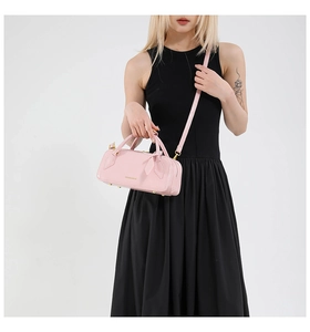 Detail of pink cylindrical Boston bag with gold FASHION & BAGS print and bow zipper