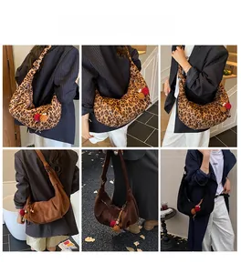 Detail view of large leopard print and solid suede crescent bags with fuzzy pompom charms