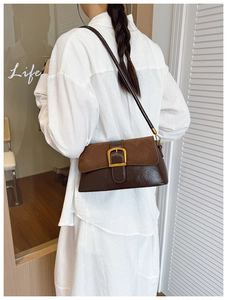 Detail showing vintage brown underarm bag with suede flap and metallic buckle closure