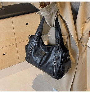 Detail of a large black leather tote bag with multi-pocket design and silver hardware