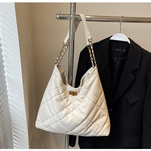 Detail of white quilted hobo bag featuring golden chain strap and twist-lock buckle