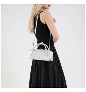 Close-up of metallic silver baguette bag showing sleek patent texture and shoulder strap