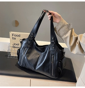 Close-up of black lychee texture leather tote bag with decorative silver zippers