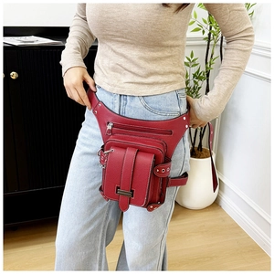 Detailed view of red textured leather waist and leg bag with silver hardware on model