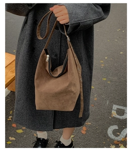 Close-up of brown suede hobo bag with metal zipper and adjustable strap details