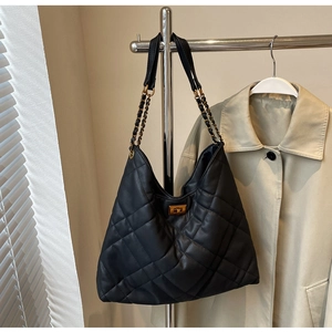 Detail of matte black quilted hobo bag featuring golden turn-lock and chain strap