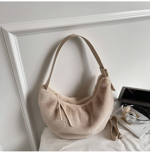 Gros plan d'un sac demi-lune en fausse fourrure beige avec bandoulières en cuir et accessoires