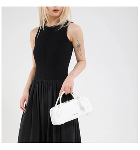 White vintage baguette bag with gold zippers held by a model in a black dress