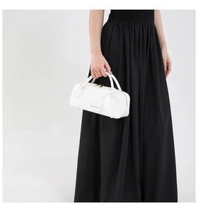 Detail of white leather baguette bag with dual handles and gold metallic hardware