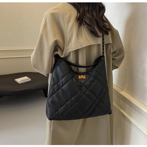 Close-up of the quilted leather texture and golden metal twist lock on a black tote bag