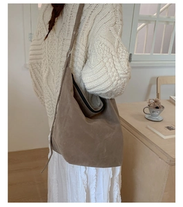Detailed view of the large brown suede hobo bag with a black zipper closure on a table