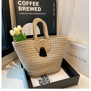 Detail of beige hand-woven tote bag with tassel and floral accents in a gift box