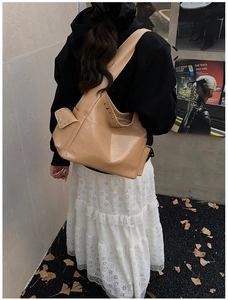 Outdoor shot of a khaki rivet hobo bag with wide shoulder strap and side pocket