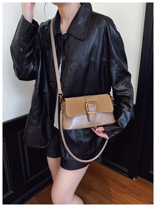 Detailed close-up of a vintage dual-tone crossbody bag with an elegant gold metal buckle