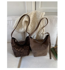 Macro detail of leopard print and coffee brown suede bucket bags with metallic zippers