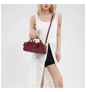 Detail of burgundy leather handbag with gold 'FASHION & BAGS' lettering and strap
