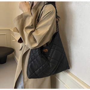Close-up of quilted leather texture and gold metal clasp on a black chain shoulder bag