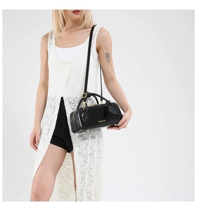 Black vintage baguette bag with gold hardware worn by model in white lace vest