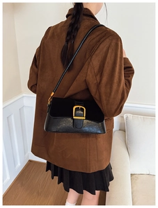 Detail of vintage black shoulder bag with gold square buckle and textured patchwork design