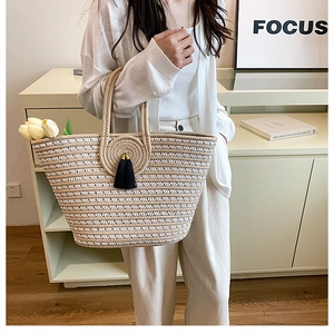 Detail of hand-woven striped tote bag with elegant floral disk and black tassel accent