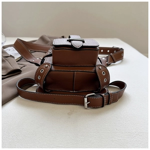 Détail de sac banane en cuir marron grainé avec boucles métalliques argentées rétro