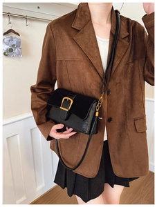 Detail of black vintage crossbody bag with gold buckle and textured leather materials