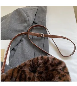 Detail of leopard print plush bag featuring brown leather adjustable shoulder strap