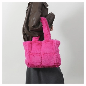 Detail of fuchsia plush tote bag with quilted pattern worn by model against grey wall