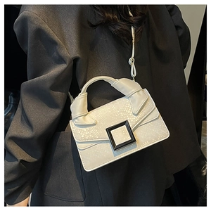 Detailed close-up of cream white snake-patterned handbag with stylish black square buckle
