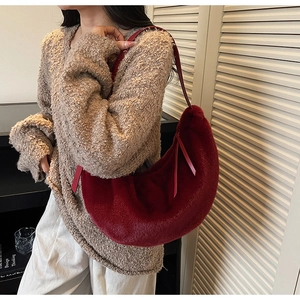 Detailed view of red plush faux fur hobo bag with sleek leather strap on model