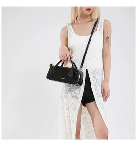 Detail of black glossy baguette bag with gold zippers and white fashion lettering print