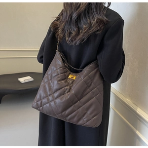Detail of quilted leather texture and gold twist lock on the dark brown shoulder bag