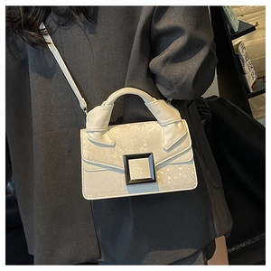 Detail of a creamy white snakeskin texture handbag with a black square buckle and handle