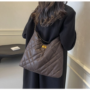 Detail of a large quilted leather tote bag with gold metal chain strap on model